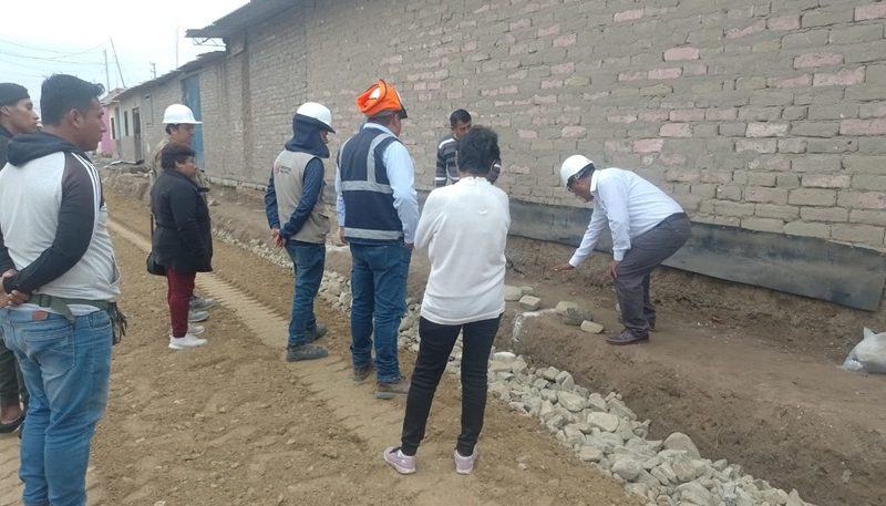 Trabajadores municipales construyendo una vereda de concreto en una calle del distrito.